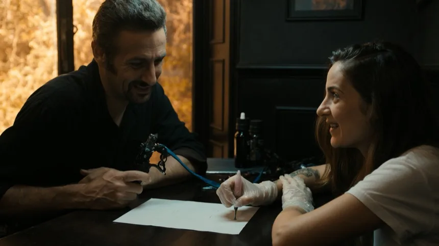 Artista y clienta revisando bocetos de tatuajes pequenos con significado sobre papel vegetal